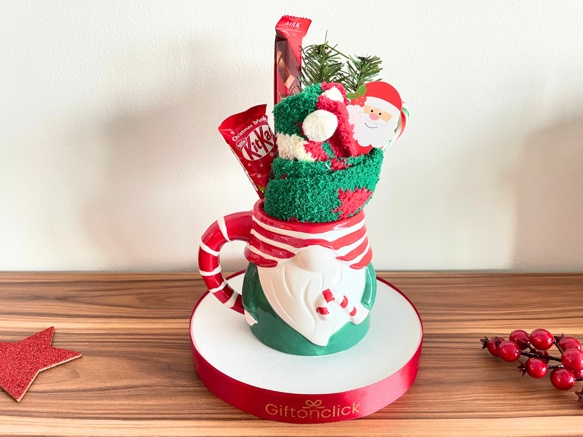 Christmas gnome mug gift set with cozy socks, holiday chocolate, and festive decorations on a round base