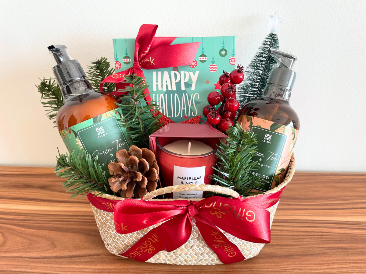 Christmas spa gift basket with Green Tea body care set, maple leaf candle, festive décor, pinecones, and red ribbon