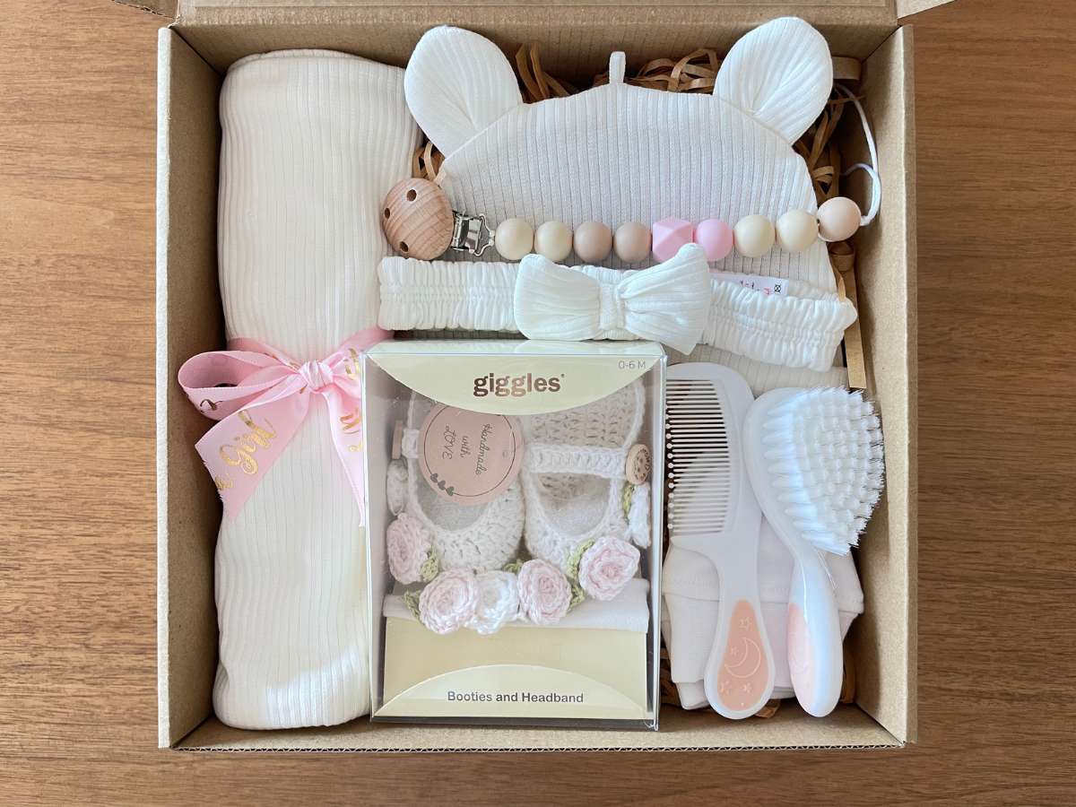 Baby gift set with items including a blanket, toys, and a box labeled 'giggles' on a wooden surface.