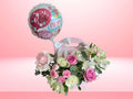 Floral arrangement with a 'Best Mom Ever' balloon on a pink background