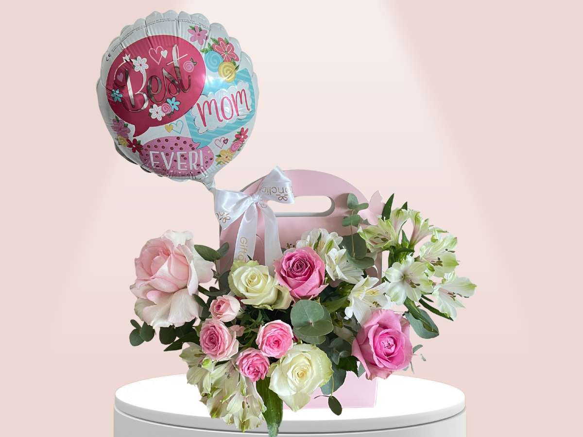 Floral arrangement with a 'Best Mom Ever' balloon on a pink background
